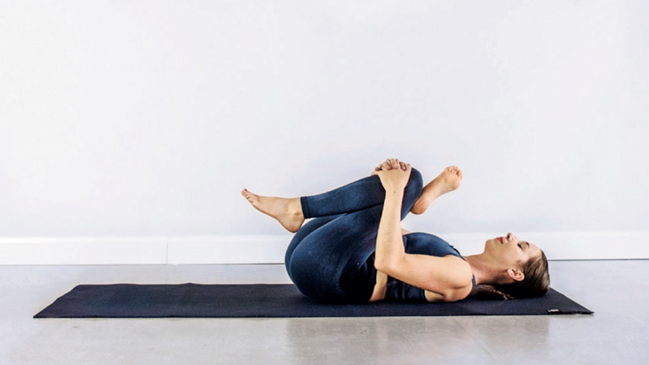 Kassandra Reinhardt reclinada en una colchoneta de yoga en forma de 4 mientras practica Yin Yoga para la luna nueva